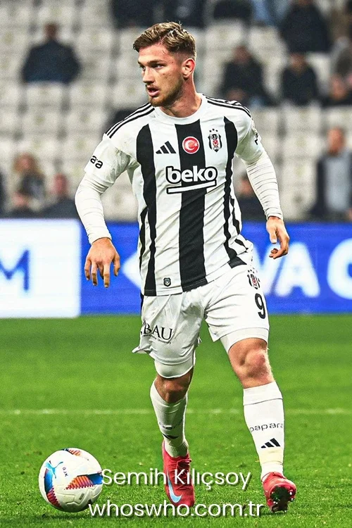 Young Turkish forward Semih Kilicsoy with short blonde-highlighted hair dribbling a soccer ball, wearing the black and white striped Besiktas jersey with the number 9 shorts and red boots.