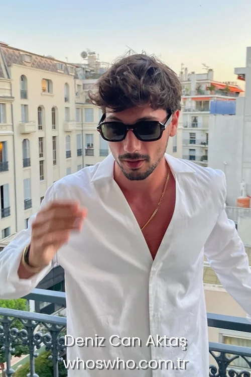 Turkish actor Deniz Can Aktas on a balcony, wearing a white button-up shirt and sunglasses