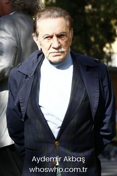 Veteran Turkish actor Aydemir Akbas wearing a plaid blazer jacket and a light blue turtleneck sweater.