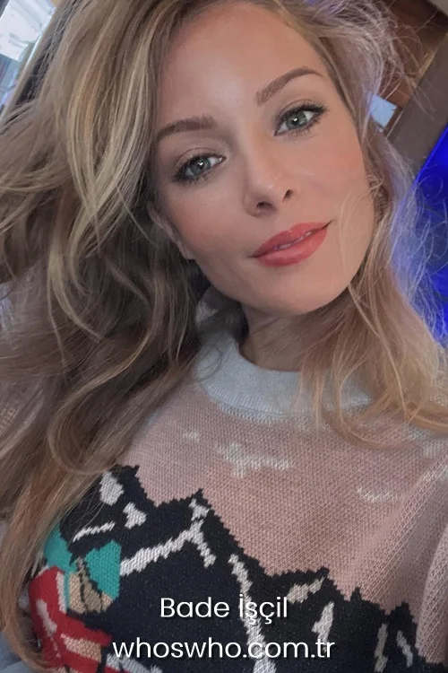 Turkish actress Bade Iscil with blonde hair and green eyes wearing a patterned knit sweater posing for a selfie