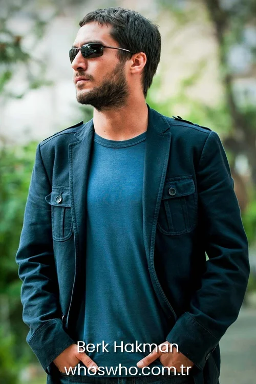 Berk Hakman wearing a dark blue jacket and sunglasses looking aside.