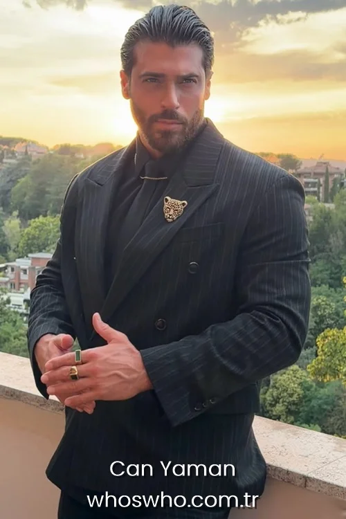 Turkish actor Can Yaman wearing a black pinstripe double breasted suit with a leopard brooch
