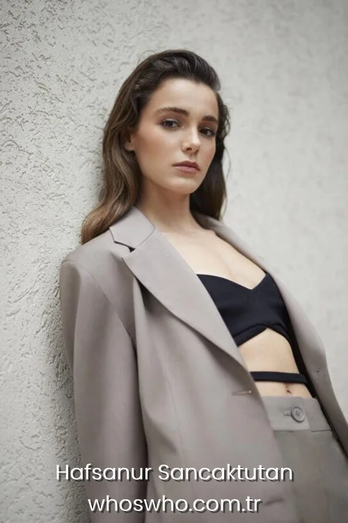 Hafsanur Sancaktutan wearing a grey blazer over a black crop top.
