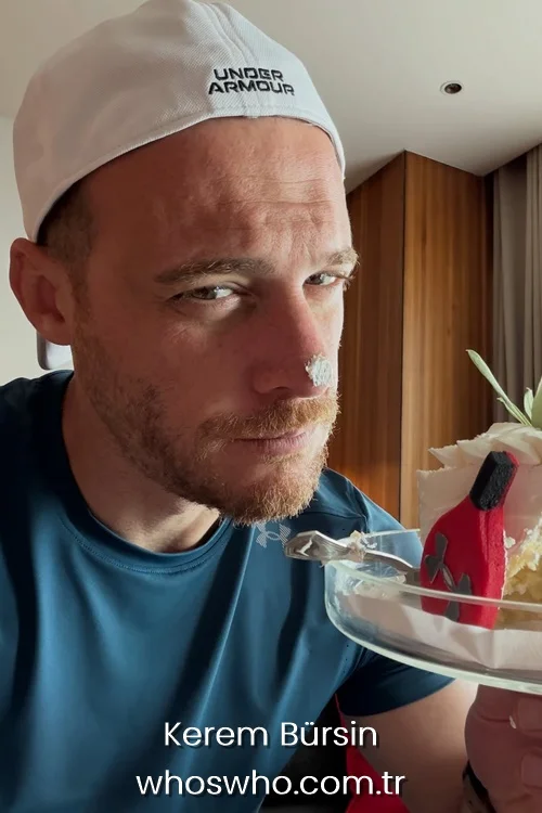 Kerem Bursin with cake cream on his nose wearing a white cap.