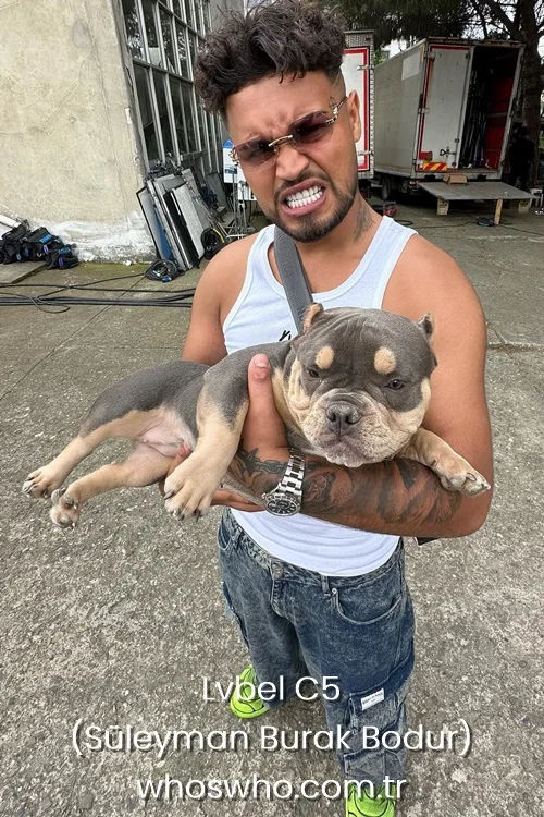 Turkish rapper Lvbel C5 holding an American Bully puppy while wearing a white tank top and sunglasses.