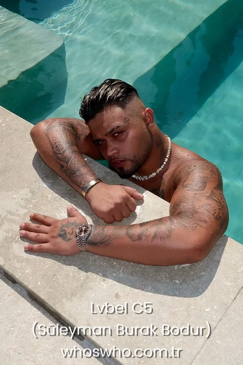 Turkish rapper Lvbel C5 with tattoos resting on the edge of a swimming pool.