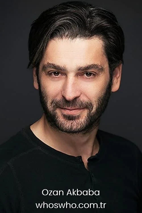 Close up portrait of Turkish actor Ozan Akbaba smiling directly at the camera wearing a black henley shirt. 