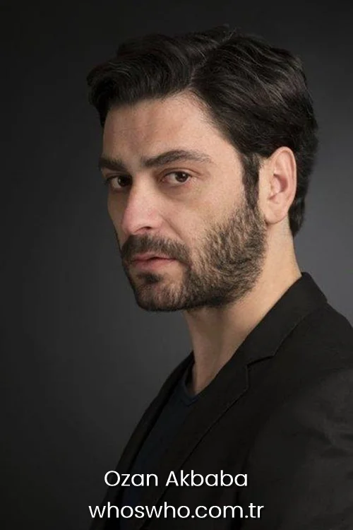 Ozan Akbaba in a side profile studio portrait wearing a black blazer with a beard.