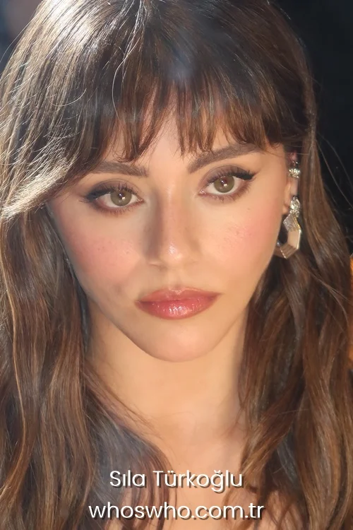 Extreme close-up portrait of Turkish actress Sıla Türkoğlu with brown eyes, soft makeup, and bangs.