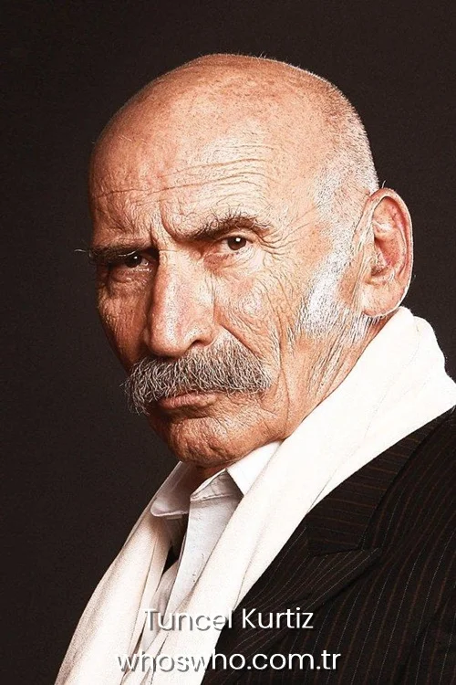 Tuncel Kurtiz close-up portrait with a mustache and a white scarf.