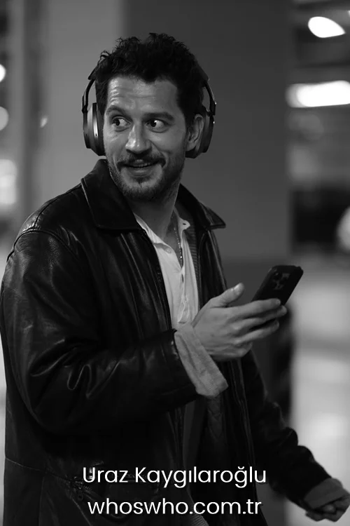 Turkish actor Uraz Kaygilaroglu wearing headphones and a leather jacket, holding a phone