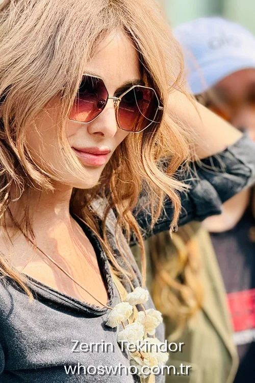 Turkish actress Zerrin Tekindor wearing geometric sunglasses and a grey top outdoors