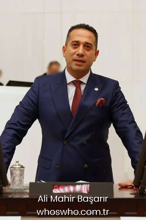 Ali Mahir Basarir speaking at the parliament podium in a navy blue suit.