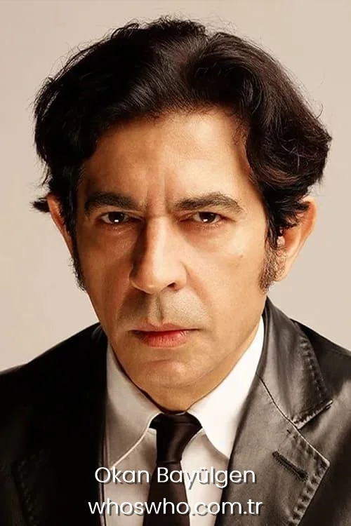 Intense close-up headshot portrait of famous Turkish presenter Okan Bayulgen looking directly at the camera with dark wavy hair, wearing a shiny black leather blazer with a white shirt and black tie.