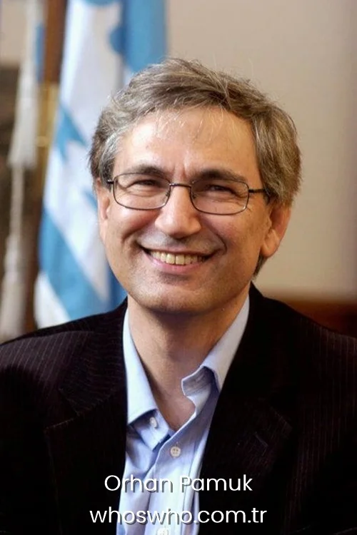 Close-up portrait of smiling Turkish author and Nobel laureate Orhan Pamuk with grey hair and glasses, wearing a dark brown corduroy blazer over a light blue collared shirt.