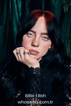 Billie Eilish with red roots and black hair wearing a black lace outfit.