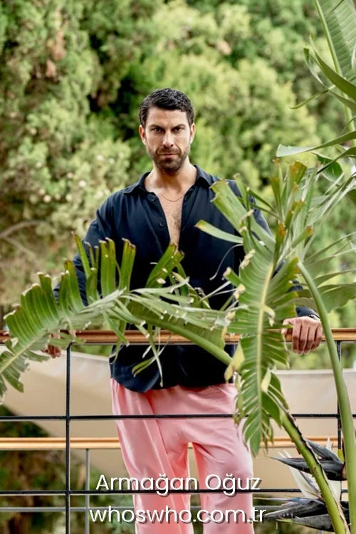 Armagan Oguz wearing a black unbuttoned shirt and pink trousers.