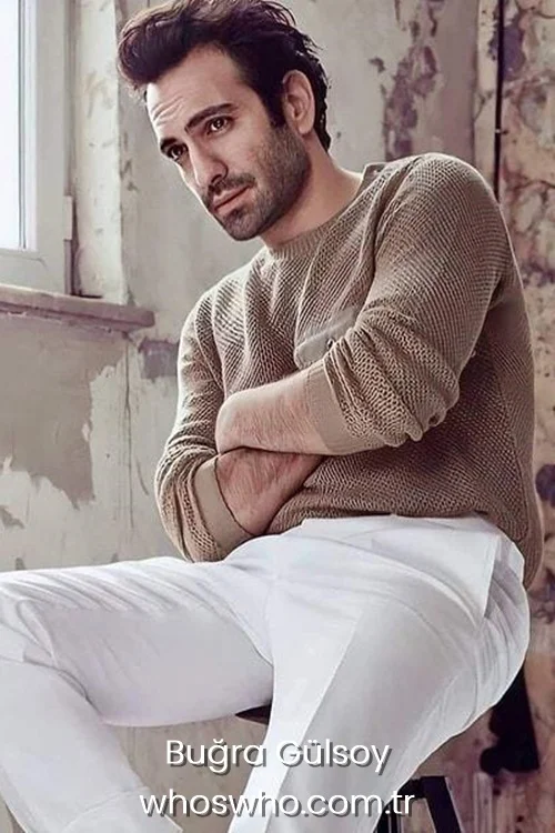 Buğra Gülsoy posing indoors in a beige sweater.