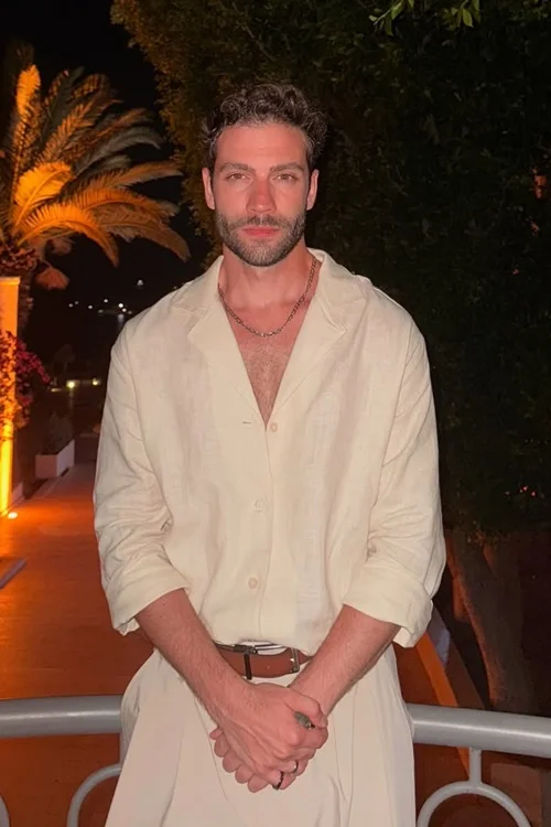 Burak Berkay Akgül posing outdoors in a light-colored outfit at night.