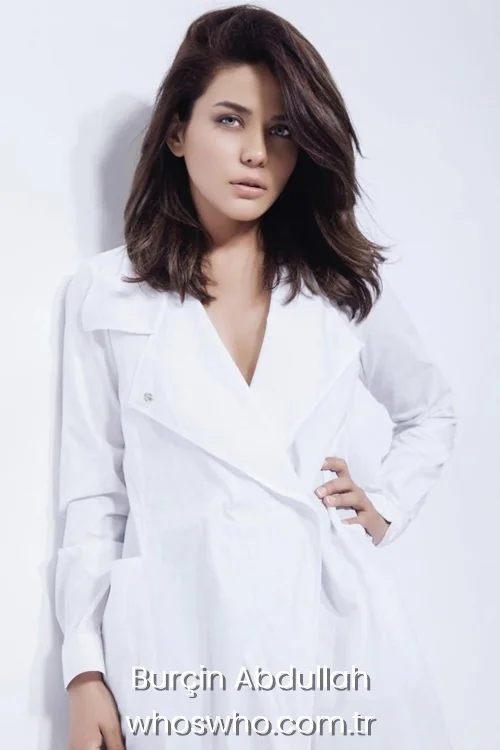 Studio portrait of Turkish actress Burçin Abdullah wearing a white outfit.