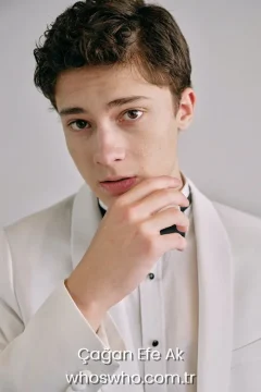 Cagan Efe Ak wearing a white tuxedo blazer with a bow tie.