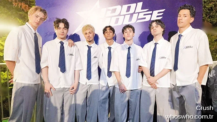 Crush 2 Group portrait of the seven young male members of the boy band Crush posing together at the Idol House debut event, all wearing matching white short-sleeved shirts, blue neckties, and light grey trousers in front of a blue promotional backdrop.