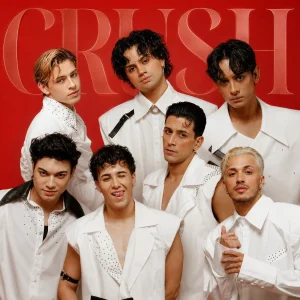 Studio promotional group photo of the six male members of the boy band Crush posing closely together against a vibrant red background featuring the text CRUSH, with all members wearing stylish, customized white outfits with black accents and rhinestone details.