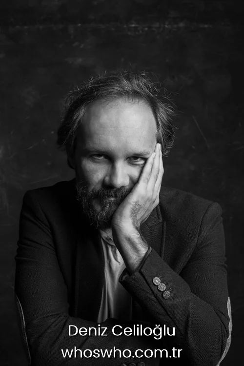 Deniz Celiloğlu 1 Black and white portrait of Turkish actor Deniz Celiloglu resting his face on his hand with a thoughtful expression, wearing a dark blazer over a light shirt against a dark background.