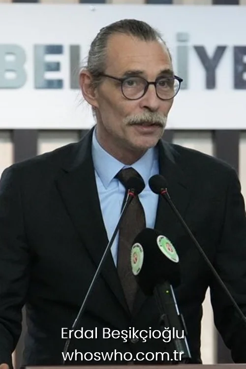 Etimesgut Mayor Erdal Besikcioglu wearing a black suit and glasses speaking behind microphones at a municipality podium