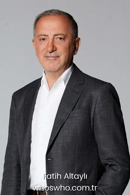 Turkish journalist Fatih Altayli wearing a dark grey blazer and a white open collar shirt posing against a light grey background