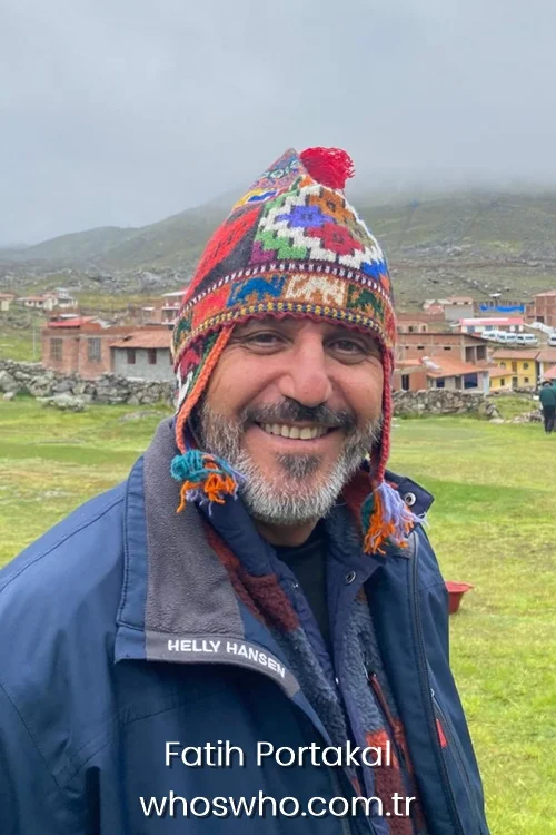 Turkish journalist Fatih Portakal smiling outdoors in a dark blue jacket and a colorful traditional knit chullo hat.