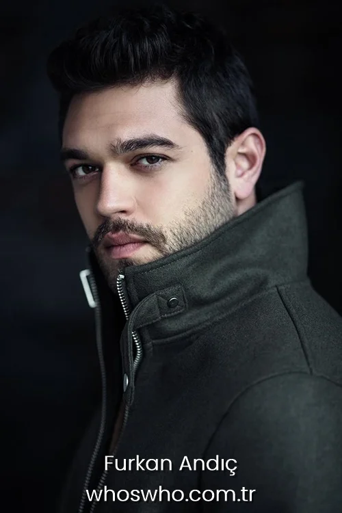 Intense close-up headshot portrait of Turkish actor Furkan Andic looking directly at the camera with dark hair and short stubble, wearing a dark olive green high-collared winter jacket against a dark background.