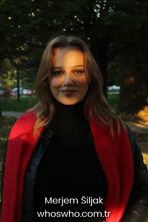  Actress Merjem Šiljak smiling in a black turtleneck and leather jacket with a bright red scarf during sunset.
