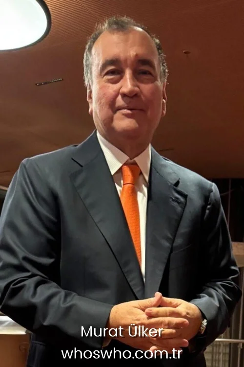 Turkish businessman Murat Ülker standing in a formal dark navy suit and orange tie for his professional profile.