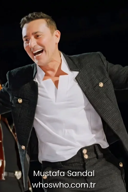 Turkish pop star Mustafa Sandal singing and smiling on stage during a live concert performance.