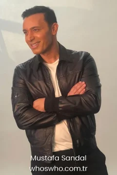 Turkish pop singer Mustafa Sandal smiling and crossing arms in a black leather jacket for his biography profile.