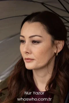 Close-up cinematic portrait of Turkish actress Nur Yazar looking away thoughtfully, featuring her long wavy brown hair, soft professional makeup, and small gold hoop earrings, with a transparent umbrella partially visible above her.