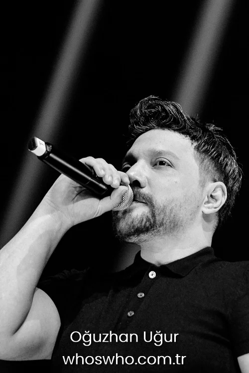 Black and white photo of Oguzhan Ugur holding a microphone on stage.