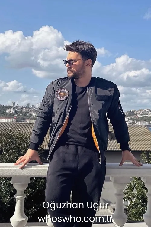 Oguzhan Ugur wearing a black bomber jacket and sunglasses outdoors.