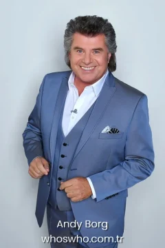 Austrian singer Andy Borg smiling in a light blue three-piece suit, official biography cover photo