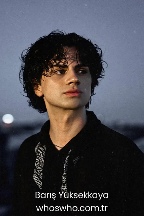 Close-up portrait of Crush boy band member Barış Yüksekkaya looking away thoughtfully outdoors at dusk, showcasing his messy curly dark hair, wearing a black shirt or hoodie with a white paisley bandana pattern print on the chest.
