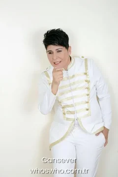 Cansever height Turkish arabesque music singer Cansever posing in a white jacket with gold military stripes pointing finger forward for a studio biography portrait