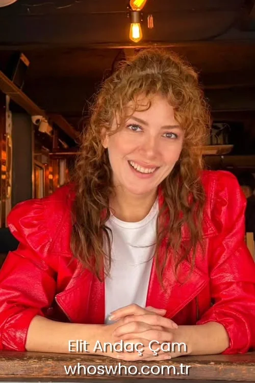 Turkish actress Elit Andac Cam smiling with curly hair wearing a bright red leather jacket over a white t-shirt 