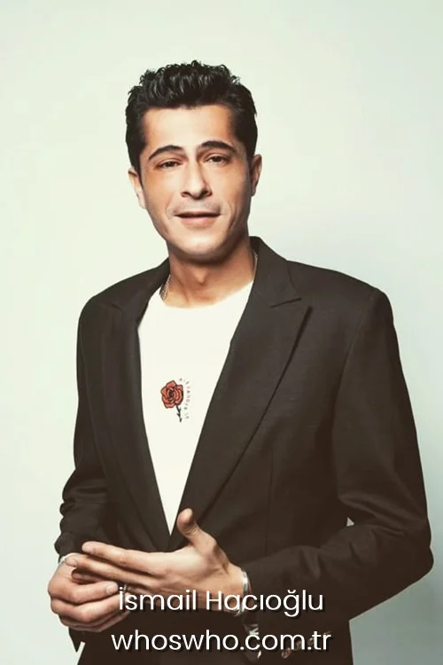 Turkish actor Ismail Hacioglu posing in a black blazer jacket and white t-shirt with a small red rose embroidery 