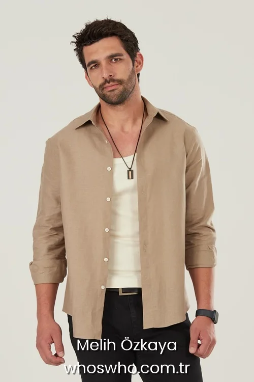 Turkish actor Melih Ozkaya in a beige linen shirt and black trousers, casual studio portrait