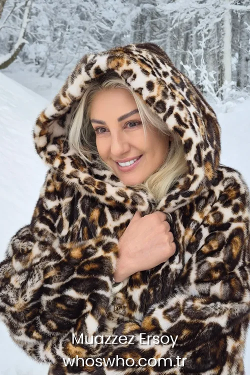 Turkish classical music singer Muazzez Ersoy smiling in a luxurious leopard print hooded fur coat against a snowy winter forest background 