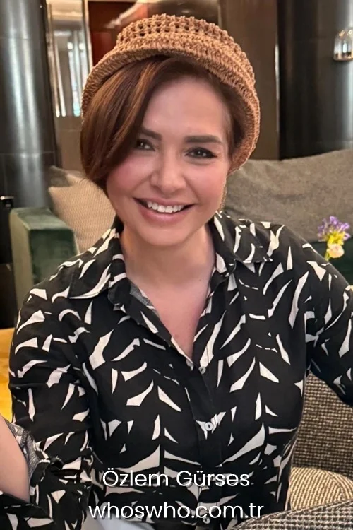 Journalist Ozlem Gurses smiling while wearing a brown woven straw hat and a patterned shirt.
