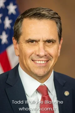 US Attorney General Todd Blanche smiling in a navy blue suit for his official biography profile cover